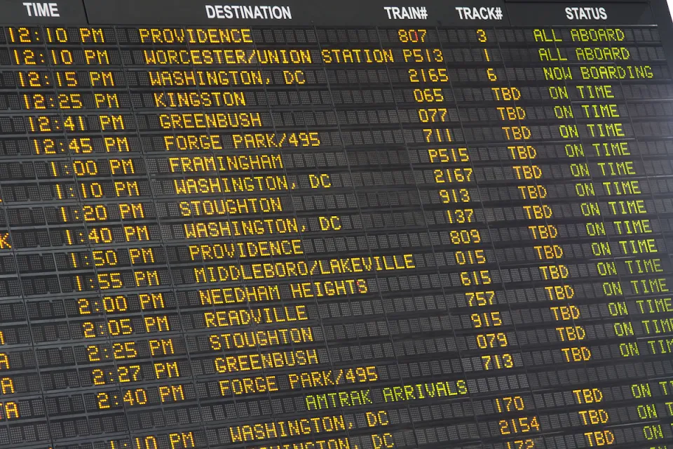 Close-up of old-fashioned trains departure board with yellow text on black background in Boston, Massachusetts train station.